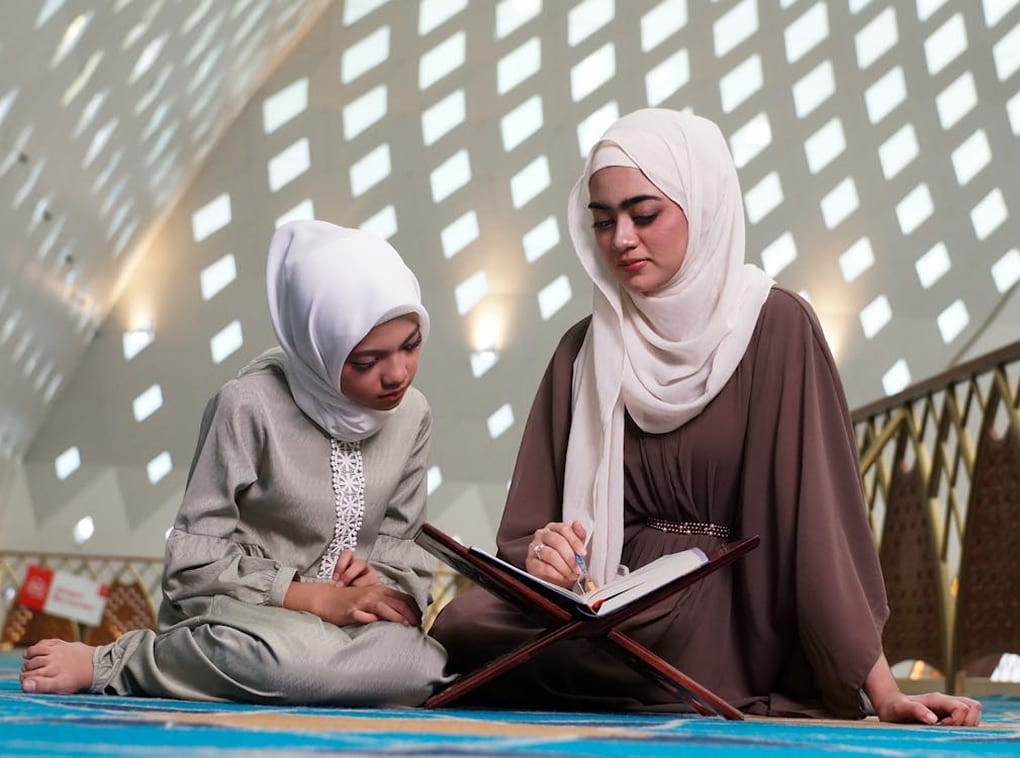 Two volunteers reading together outdoors under dappled light