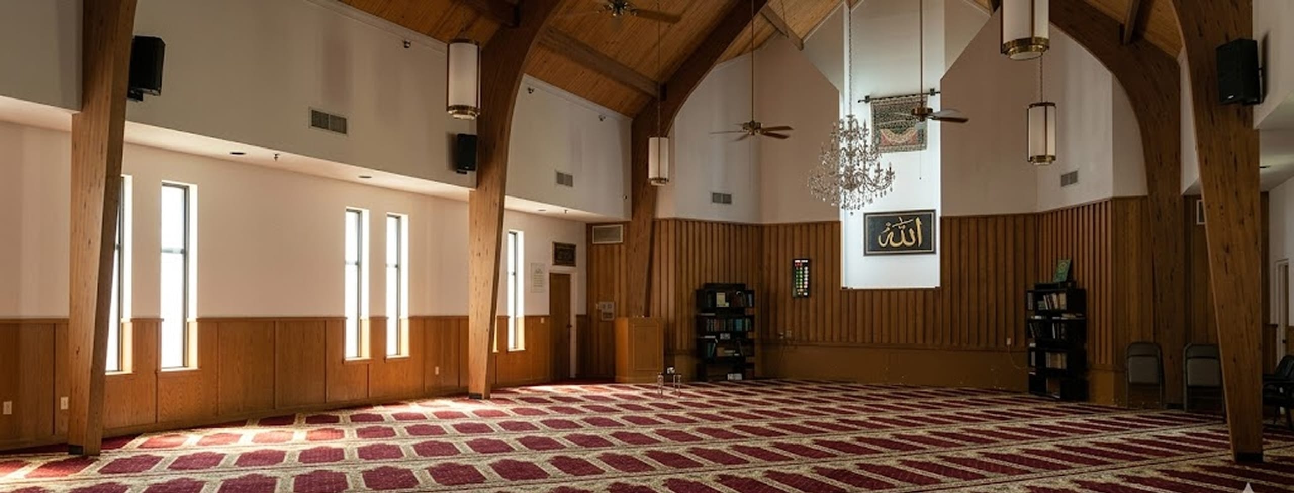 The prayer hall of the Islamic Center of Southlake with its chandelier, wood panelling and patterned carpet